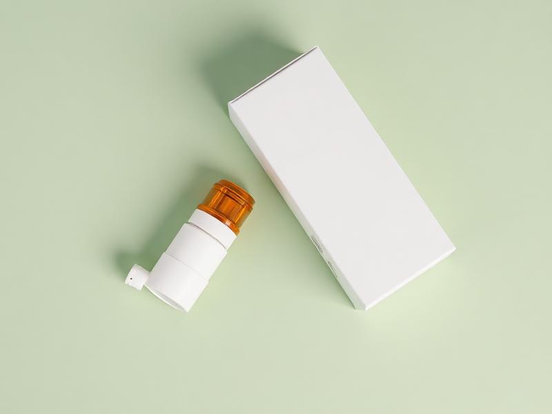 Naloxone nasal spray device beside its packaging on a sage green background